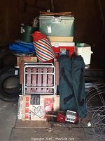 Full view of camping gear lot items stacked and arranged, showing coolers, tarps, folding chairs, and carrying bags.