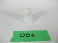 Front view of small white marble polar bear figurine against white background with green label beneath