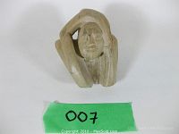 Front view of hand carved stone figurine showing face and arm position.