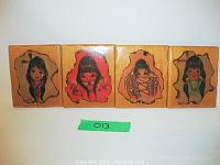Four lacquered wood panels depicting native children in colorful traditional clothing against natural wood backgrounds.