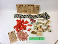 Overall view of Bingo cards, red plastic chips, round number tokens, and assorted wooden craft stamps spread on a surface.