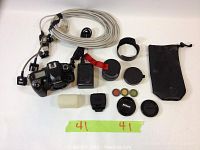 All items laid out: camera body, lens, charger, cord, caps, filters, hood, pouch, diffuser