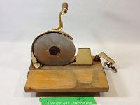 Side view showing wooden base, metal blade housing, and hand crank with wooden handle.