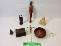 All items arranged together on white background showing Virgin Mary wax candle, Buddha statues, Christ crucifix, bowl, boxes, pyramid and prism.