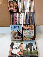 Photo showing a variety of DVDs including Grease, Mamma Mia, The Kids Are All Right, Silver Linings Playbook, and The Blind Side.