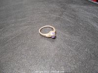 Photo showing sterling silver band with light purple oval stone on a black surface.