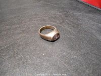 Image showing sterling silver amethyst ring lying on a smooth dark surface, displaying the side and top profile of the ring and stone shape.