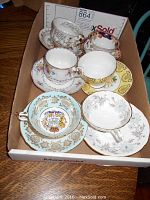 Overview of the 6 tea cups and saucers in a box showing various patterns and colors.