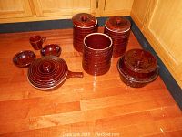 Photo showing full set of Mar-Crest stoneware items: 3 cookie jars, 2 soup bowls, 1 mug, pot with lid, bean pot with lid, all brown glazed with circular ridged pattern