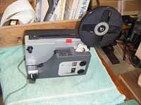 Side view of the Sankyo Dualux 1000 projector showing the reel attached and the power cord.