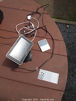 Sony Nav-U GPS device and white Apple iPod Classic placed on a wooden surface with cables