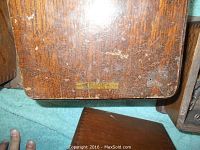 Bottom side of one wooden ringer box showing scratches and a small label.