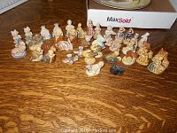 Approx. 38 Wade Red Rose Tea ceramic figurines laid out on wood surface, showing a mix of human and animal shapes with muted paint tones.