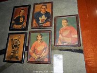 Overview of all five vintage framed hockey pictures arranged on carpet showing five hockey players in their classic NHL jerseys.
