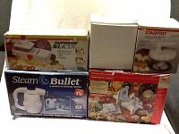 Five small appliances packaged mostly in original boxes including the Steam Bullet, Starfrit Supreme Slicer, World Cuisine Turning Slicer, and Starfrit manual food processor.