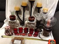 Photo showing an assortment of candle holders including candelabra, resin cherub holders, glass holders, ceramic elephants, and votive candles.