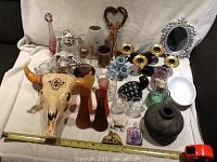 Full view of all items displayed on light cloth background showing all various decor pieces including ceramic bull skull, glass vases, figurines and candle holders.