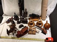 Full view of the mixed wooden items arranged showing carved bears, tribal statues, candlesticks, toys, and boat.