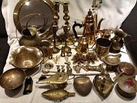 Full view of the lot including brass watering can, porthole mirror, coffee pot, candlesticks, and various small brass decorative items.