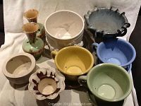 Overview of all ceramic items showing coffee cups, vases, planters including three colorful coffee cups and various small pots