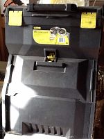 Stanley rolling tool box closed front view with key locks and handle visible. The box is black and heavily marked with dirt.