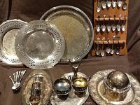 Photo of 4 round silverplate trays, 2 smaller oval trays, 6 Tudor plate spoons, creamer, sugar bowl, napkin rings, lidded bowl all arranged on a dark cloth