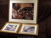 Three framed Parisian themed prints including one large and two smaller prints, arranged on a dark surface.
