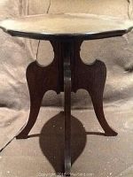 Side angle showing the tripod base with curved legs and scalloped edges on the tabletop.