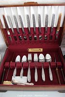 Open view of the flatware set showing knives, forks, spoons, coffee spoons, and steak knives arranged in slots with a Community brand nameplate.