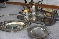 Full view of silver-plated tea set with large serving tray and additional trays including handled bread tray and small tray