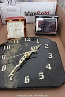 Three clocks in a box: stone wall clock in front and two travel clocks behind it