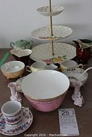 Overall display of the china collection showing the tiered dessert tray, Noritake bowl, assorted cups, creamers, and small decorative porcelain pieces.