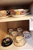 Shelf view showing multiple assorted floral bone china tea cups and saucers
