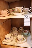 Wide shot of twelve tea cups and saucers displayed on wooden shelves
