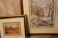 Two framed and matted prints side by side, one depicting a snowy mill stream scene, the other a rural fall haymaking scene.