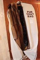 Full length mink coat in brown tones inside a fur coat storage bag labeled 'Fur Coat Bag'.