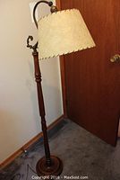 Full view of wood base floor bridge lamp with cream textured shade and brass fittings.