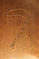Full view of the gold chain with the initial pendant laid out on wooden surface.
