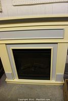 View of the full electric fireplace with cream/yellowish frame and gray decorative panels on front