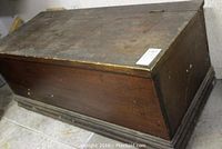 Side angle view of the vintage wooden storage chest showing the hinged lid closed and the base with stepped molding.