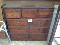 Front view of vintage wooden chest of drawers with multiple drawers and round knobs.