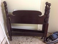 Twin wooden headboard with rounded finials showing wear and general use marks