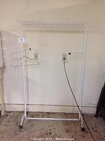 White metal clothing rack with wheels and two extendable side arms, hanging hanger included.