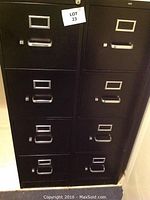 Photo of two black metal file cabinets side by side with four drawers each and label holders on each drawer.