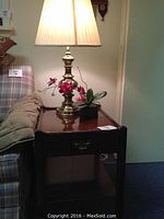 End table with brass lamp and floral decoration beside a couch