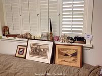 Overview shot of assorted framed art and decor items on window ledge and couch backrest.