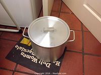 Photo of a large aluminum canning pot with lid, placed on floor mat