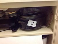 Black speckled enamel cookware and metal roasting pan stacked together on shelf