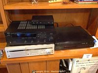 Yamaha stereo receiver, Harmon cassette deck, and a black media player on wooden shelf