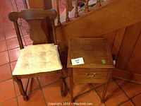 Wooden chair with cushioned seat next to wooden sewing cabinet with drawer and curved legs.